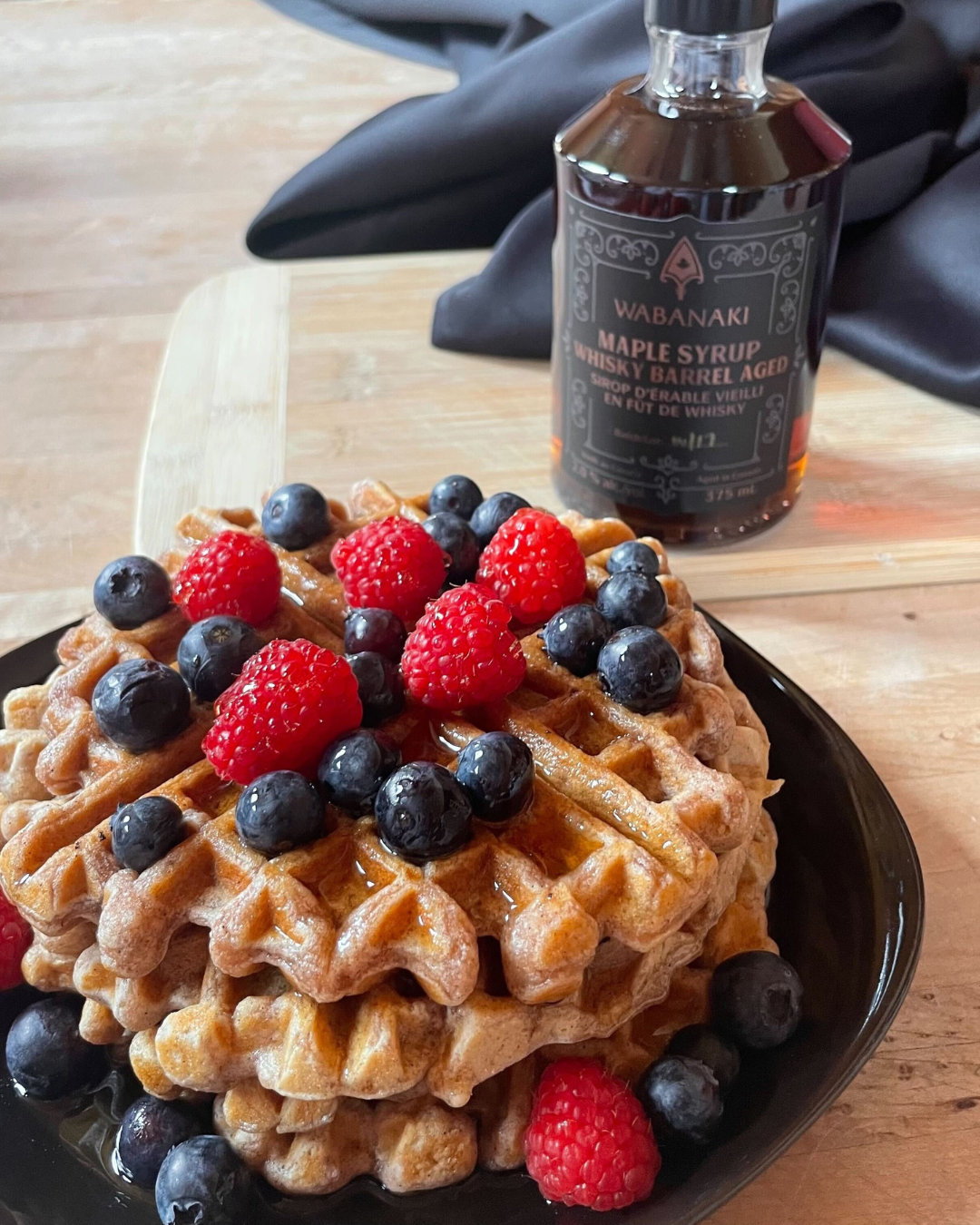 Belgian waffles topped with raspberries, blueberries and Wabanaki Maple Whisky Barrel aged Maple Syrup