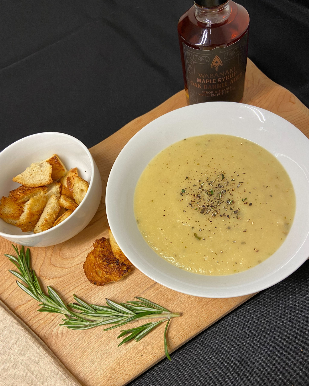 Roasted Parsnip Maple Soup pictured in the bowl along with Wabanaki Maple Syrup and a picture of potato wedges in a white bowl